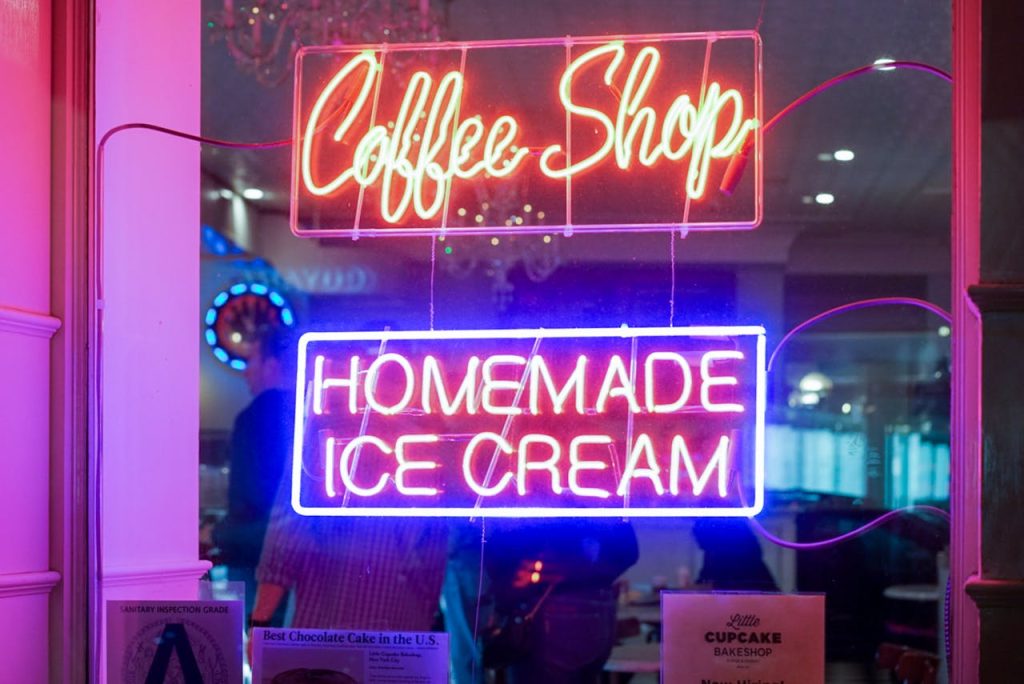 Vibrant neon signs for a coffee shop and homemade ice cream displayed indoors.